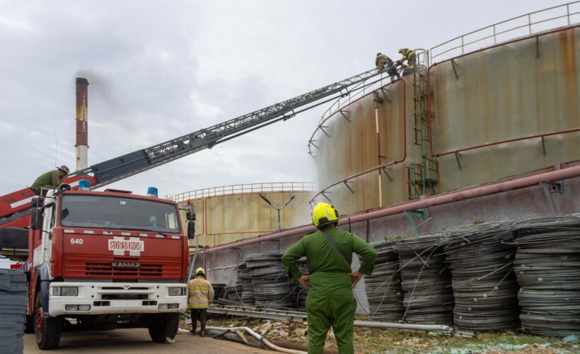 Miembros de comandos de bomberos del territorio mantienen vigilancia sobre el tanque de combustible (crudo nacional) incendiado en la mañana del viernes último