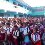 El próximo 1ro de septiembre, Cuba vivirá el inicio de un nuevo curso escolar, un esfuerzo que ha requerido de soluciones creativas y el compromiso de todos los sectores para enfrentar complejas realidades. Así lo expusieron la ministra de Educación, Dra.C. Naima Ariatne Trujillo Barreto; la viceministra primera del Ministerio de Industria, Yamilin González Milian; y el director de Comercio Mayorista del Ministerio de Comercio Interior, Ihosvany Montero García, durante la emisión de la Mesa Redonda dedicada a la preparación del período docente. La ministra de Educación, Dra.C. Naima Ariatne Trujillo Barreto, destacó el compromiso y la capacidad de cada territorio para encontrar variantes propias y priorizar sus recursos. “Cada proyecto educativo se tiene que parecer a su territorio, a las condiciones”, afirmó, subrayando la flexibilidad del sistema. Un ejemplo emblemático es Santiago de Cuba, un territorio que, según Trujillo Barreto, “tiene hoy un 99% de su cobertura docente” y ha encontrado “muchísimas variantes, incluso para poder tener algunas iniciativas para aseguramientos tecnológicos”. Reconoció que la situación no es homogénea en el país, pero resaltó la unidad: “Nos encontramos trabajadores de todos los sectores así unidos. Eso creo que es algo que pudimos apreciar en todas partes”. La búsqueda de respuestas a nivel municipal y comunitario ha sido una característica singular de este año. La ministra explicó que el perfeccionamiento del sistema educativo y las propias necesidades han impulsado alianzas. “Hemos aprendido también en el trabajo en redes y las soluciones en los municipios. Y entonces hay una respuesta más estable”, aseguró. Esto se ha traducido en vínculos inéditos para el mantenimiento de las escuelas. “Hoy lo mismo nos podemos encontrar en la escuela rural, donde una cooperativa está aportando, que la labor de familias que se unen o empresas de determinada área de producción con una respuesta”. Un testimonio conmovedor de esta resiliencia es la provincia de Guantánamo, severamente afectada por eventos climatológicos. “Guantánamo va a estar recuperando la última institución educativa pendiente, el propio 1ro de septiembre, en una comunidad rural donde no quedó nada de la escuela”, anunció la ministra, destacando el trabajo intenso de su gente. Más de 1 500 000 estudiantes cubanos, desde el preescolar hasta el preuniversitario, incluidas las escuelas especiales y de formación profesional, iniciarán el curso escolar el 1 de septiembre. El papel de la industria Por su parte, Yamilin González Milian, del Ministerio de Industrias, detalló los desafíos para asegurar productos esenciales como libretas y, sobre todo, los uniformes escolares. Ante una demanda total de más de 3.6 millones de prendas, la industria solo pudo financiar y producir 2.2 millones. El mayor reto, explicó, ha sido la contingencia energética: “La disponibilidad de combustible para el traslado y la recuperación de todas las prendas una vez producidas”. La solución, una vez más, ha venido de la coordinación y el apoyo mutuo. “Hemos trabajado muy coordinados con los gobiernos territoriales”, dijo. Relató cómo se utilizaron grupos electrógenos en fábricas de Villa Clara, Santiago de Cuba y otros territorios para mantener la producción durante los apagones, e incluso cómo provincias como Guantánamo y Santiago, al terminar sus compromisos, apoyaron a Gramma, una de las más afectadas por la falta de electricidad. La prioridad fue cubrir los grados iniciales (preescolar, 5° y 7°), cuyos uniformes ya están en el comercio. La producción continuará en septiembre y octubre para completar alrededor de 800 000 prendas más para el primer año y otros grados. La viceministra rindió homenaje a los colectivos mayoritariamente femeninos de la industria: “Son mujeres que tienen que atender a nuestras familias y han hecho un esfuerzo enorme, con un tremendo compromiso”. En ese sentido, la ministra de Educación señaló que en este proceso convergen los tiempos de la industria, del comercio y la familia. El más importante es el de la familia, que es a quien se debe tributar. El acto de preparación de las aulas también refleja esta diversidad de soluciones. Sobre las imágenes de aulas con libros dispuestos en los pupitres, la ministra aclaró que “las escuelas de conjunto con su familia tienen diversas variantes”. En algunos casos las familias acuden estos días a la escuela, otras recuperan libros usados, y “ha habido una tradición en los últimos años de que muchas aulas y profesores prefieren recibir así con ese orden”. La Dra.C. Naima Trujillo envió un mensaje de reconocimiento: “No habrá ningún territorio de Cuba que no haya hecho el mayor esfuerzo. Estamos muy motivados, nos anima mucho, nos impulsa además a hacer mejor las cosas”. El comercio interior en este proceso Foto: Tomada del sitio oficial de Ministerio del Comercio Interior. En otro momento de la Mesa Redonda, Ihosvany Montero García, director de Comercio Mayorista del Ministerio de Comercio Interior, señaló que su organismo mantiene un aseguramiento para el inicio del nuevo curso que busca conciliar la producción y comercialización, en un escenario donde la distribución del uniforme escolar es tarea de primer orden. “Desde el pasado 15 de julio comenzó en Cuba la comercialización del uniforme, dando prioridad a los grados iniciales de primaria y secundaria. Actualmente tenemos vendido más del 80% de estas piezas, equivalente a unas 500 000 prendas”, dijo Montero García. Explicó que, si bien se espera entregar a los estudiantes dos uniformes, hasta el momento se comercializa solo uno y el otro se distribuirá más adelante. Comentó que existe un sistema que permite recibir información sobre las ventas desde todo el territorio nacional, y el inicio de la comercialización en julio permitió disminuir la aglomeración de personas en los puntos de venta. “Para una segunda etapa estamos evaluando la venta de uniformes a los estudiantes de enseñanza pedagógica, primer año de preuniversitario y enseñanza técnico profesional”. Según Montero García, algunos territorios del país ya comercializan tallas más grandes destinadas a estos estudiantes. Ultimando detalles Pioneros de la escuela primaria Guerrillero Heroico. Foto: Enrique González (Enro)/ Cubadebate. Una escuela pedagógica de Pinar del Río, fundada por Fidel el 1ro de septiembre de 1975, será escenario de el acto central por el inicio del curso escolar en el país. No obstante, cada provincia tendrá su propia celebración, tanto en plazas abiertas, como en instituciones relevantes de la comunidad, pues, en palabras de la ministra de Educación, “el hecho educativo es un hecho social transversal a toda la familia”. Entre las novedades del período lectivo que se avecina, Naima Ariatne Trujillo Barreto mencionó el tercer perfeccionamiento, proceso a partir del cual se introdujo una transformación del tercer grupo de grados (tercero, sexto, noveno y duodécimo). “Los materiales y textos han llegado de forma paulatina y, entre septiembre y octubre, arribarán al país los del tercer grupo, que se han obtenido con mucho esfuerzo”, señaló. Comentó que una de las prioridades del tercer perfeccionamiento es desarrollar un curso donde la comunicación sea prioritaria. “Pretendemos continuar fortaleciendo el trabajo educativo integral con materiales curriculares, pero sobre todo con formación integral, que ventile temas vinculados con la droga, el embarazo en la adolescencia, entre otros preocupantes en la sociedad”, comentó. También mencionó a la importancia de preparar a los integrantes del sistema educativo ante la inminente publicación del nuevo Código de la Niñez, las Adolescencias y las Juventudes. En ese camino, el próximo curso escolar en Cuba se presentará como un testimonio de la capacidad del pueblo para buscar soluciones, incluso en medio de la adversidad.